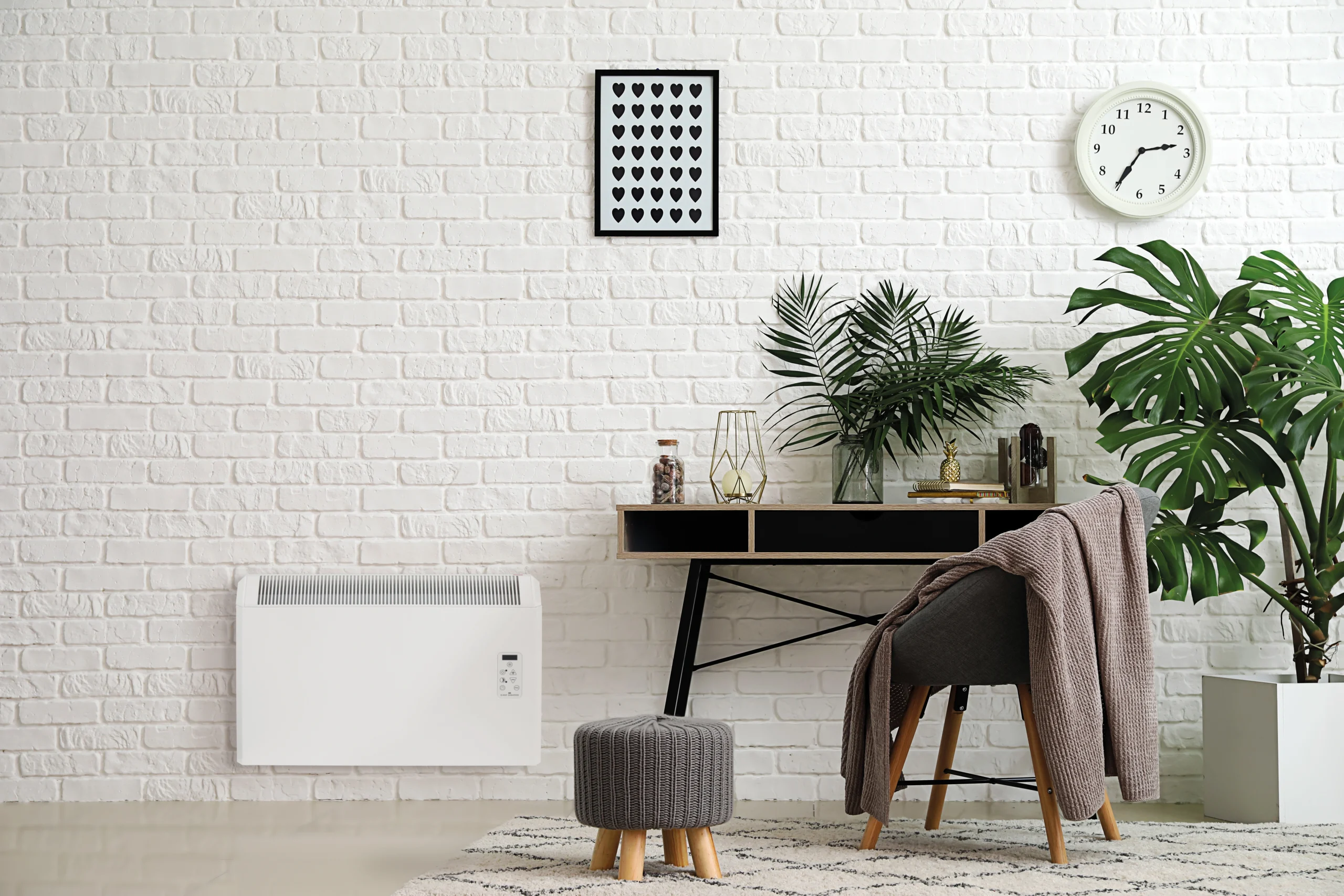 The Elnur panel heater installed on a brick wall, with a wooden desk beside it.